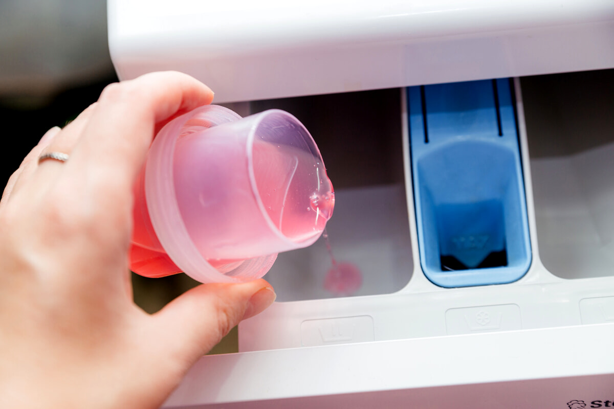 perche rimane acqua nella vaschetta ammorbidente | vaschetta ammorbidente con mano che versa del detersivo